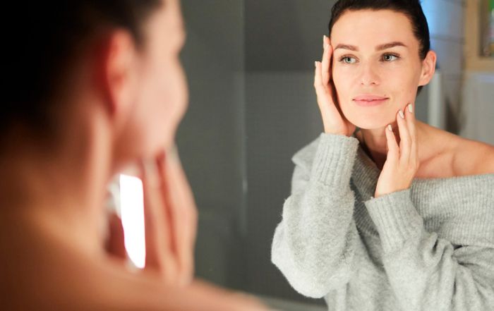 mujer echándose crema de aove