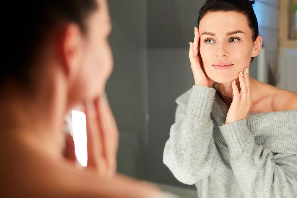 mujer echándose crema de aove